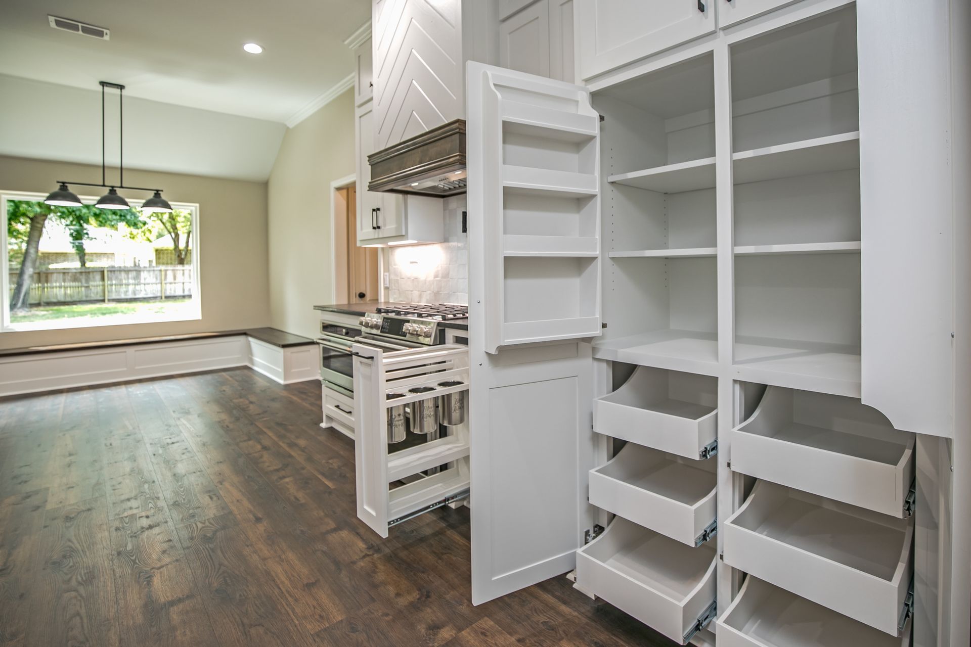 A kitchen with a pantry with drawers pulled out of it.