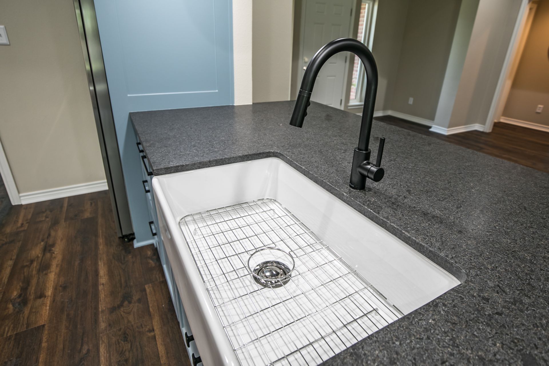 A kitchen sink with a black faucet on a granite counter top.