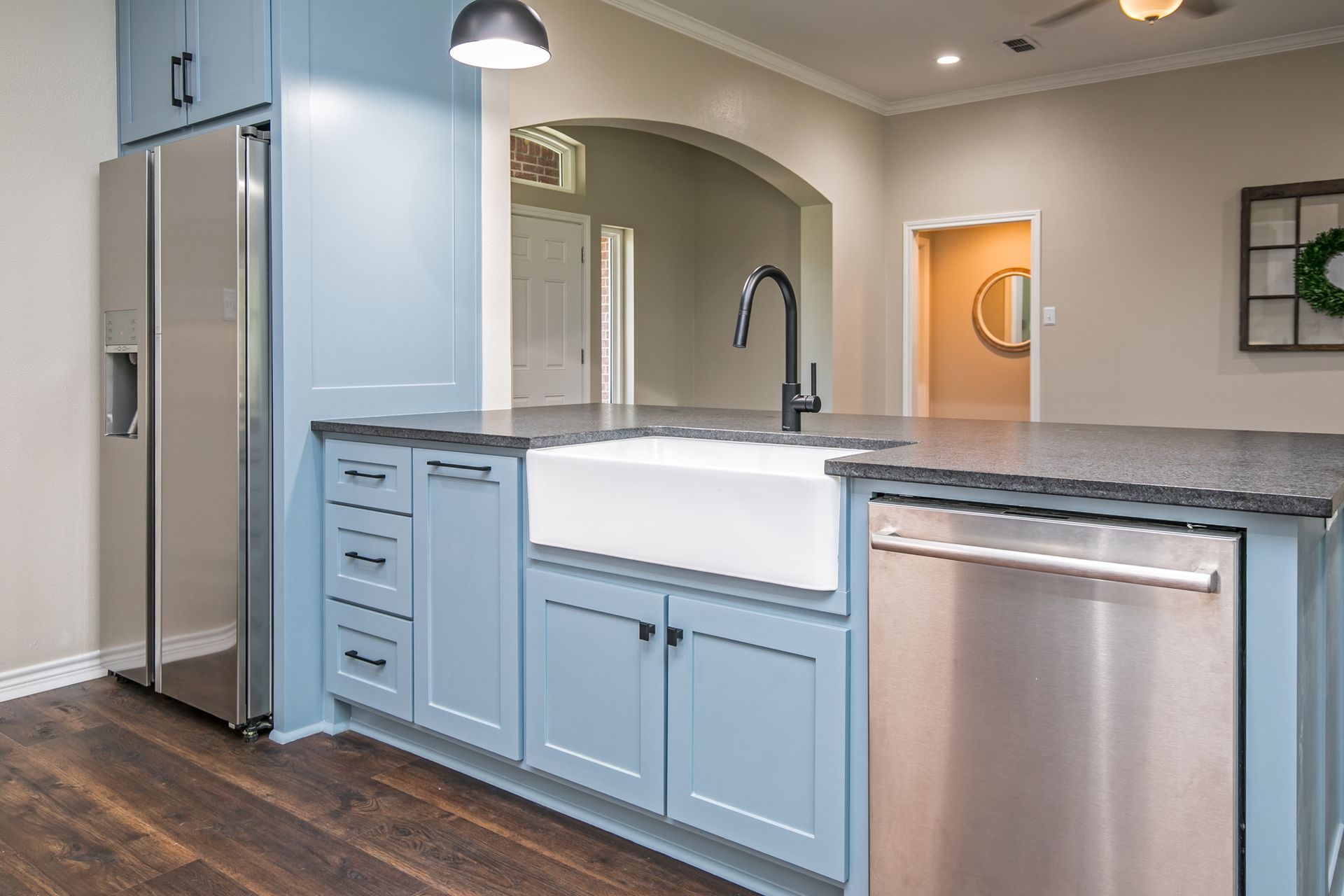 A kitchen with blue cabinets , stainless steel appliances , a sink and a refrigerator.