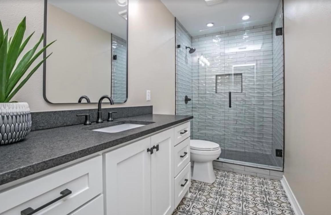 A bathroom with a toilet , sink , mirror and walk in shower.