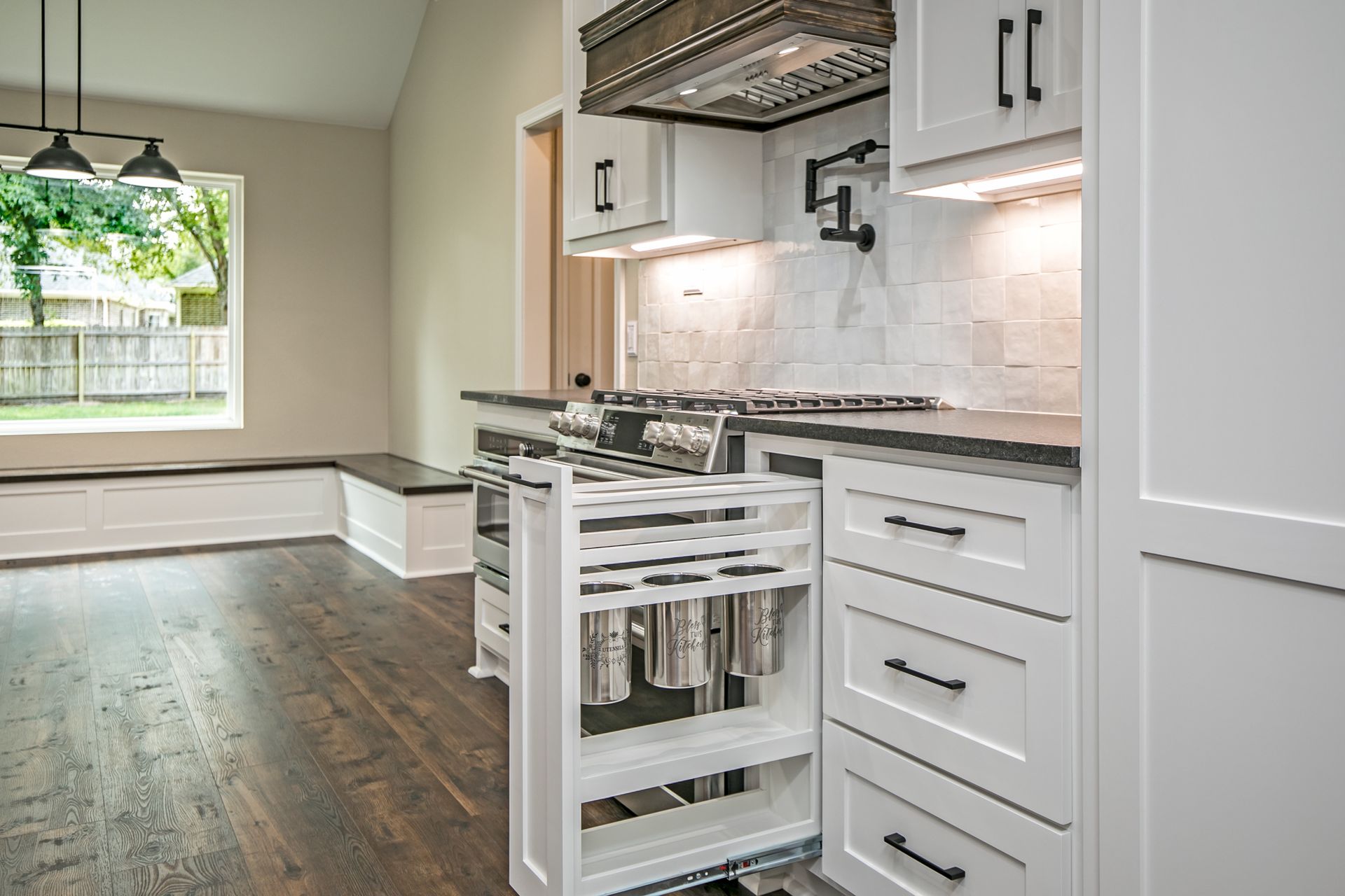 A kitchen with white cabinets and a pull out spice rack.
