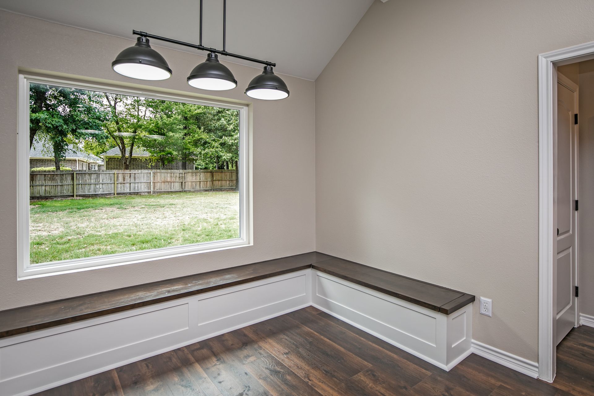 An empty room with a large window and a bench in front of it.