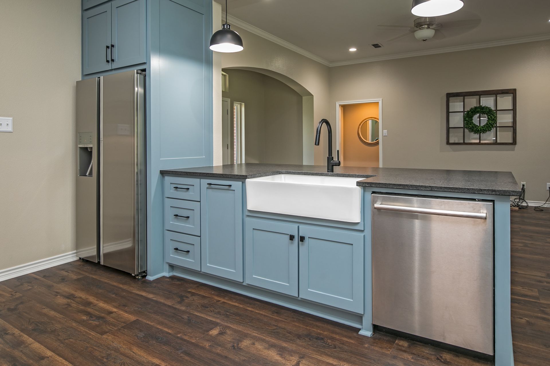 A kitchen with blue cabinets , stainless steel appliances , a sink and a refrigerator.