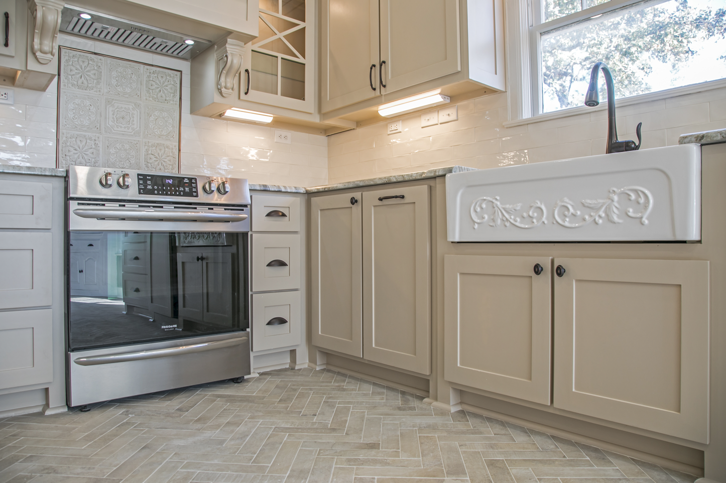 A kitchen with a stove , sink , and cabinets.
