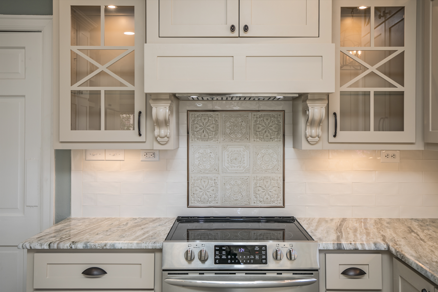 A kitchen with white cabinets and a stove top oven.