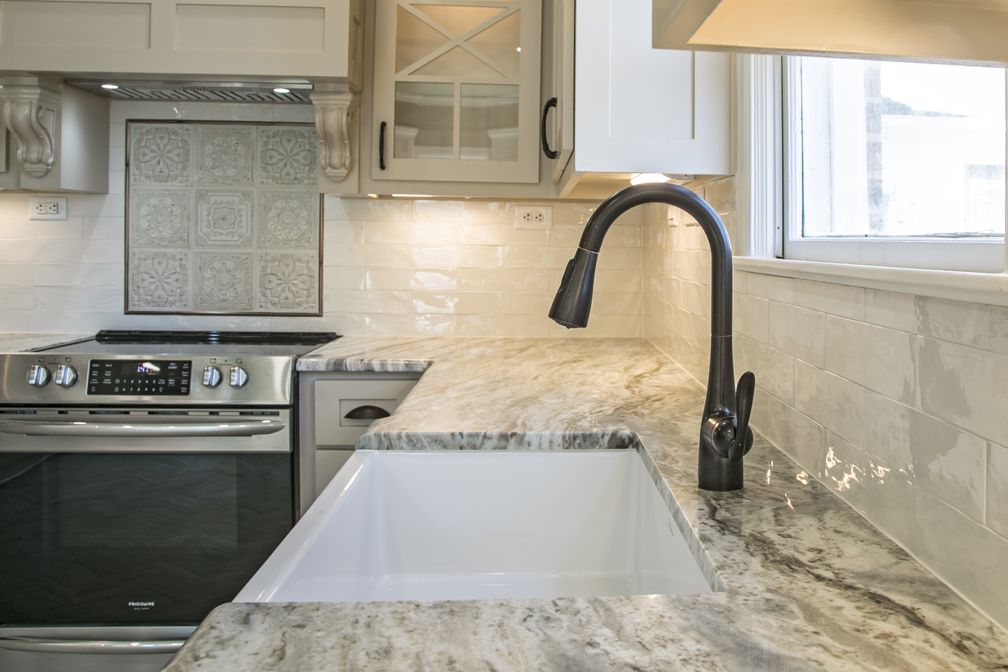 A kitchen with a sink , stove and oven.