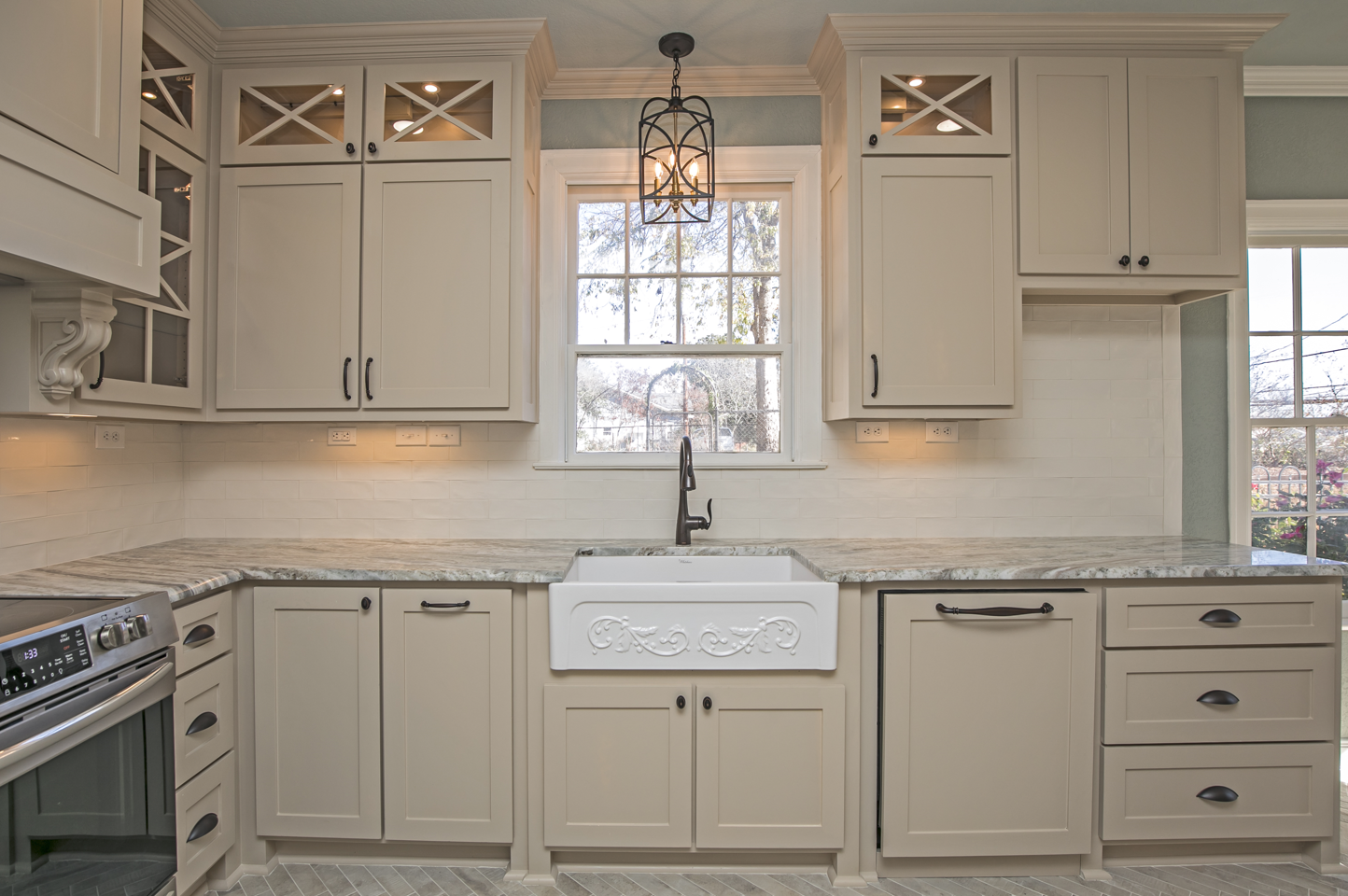 A kitchen with white cabinets , granite counter tops , a sink and a window.