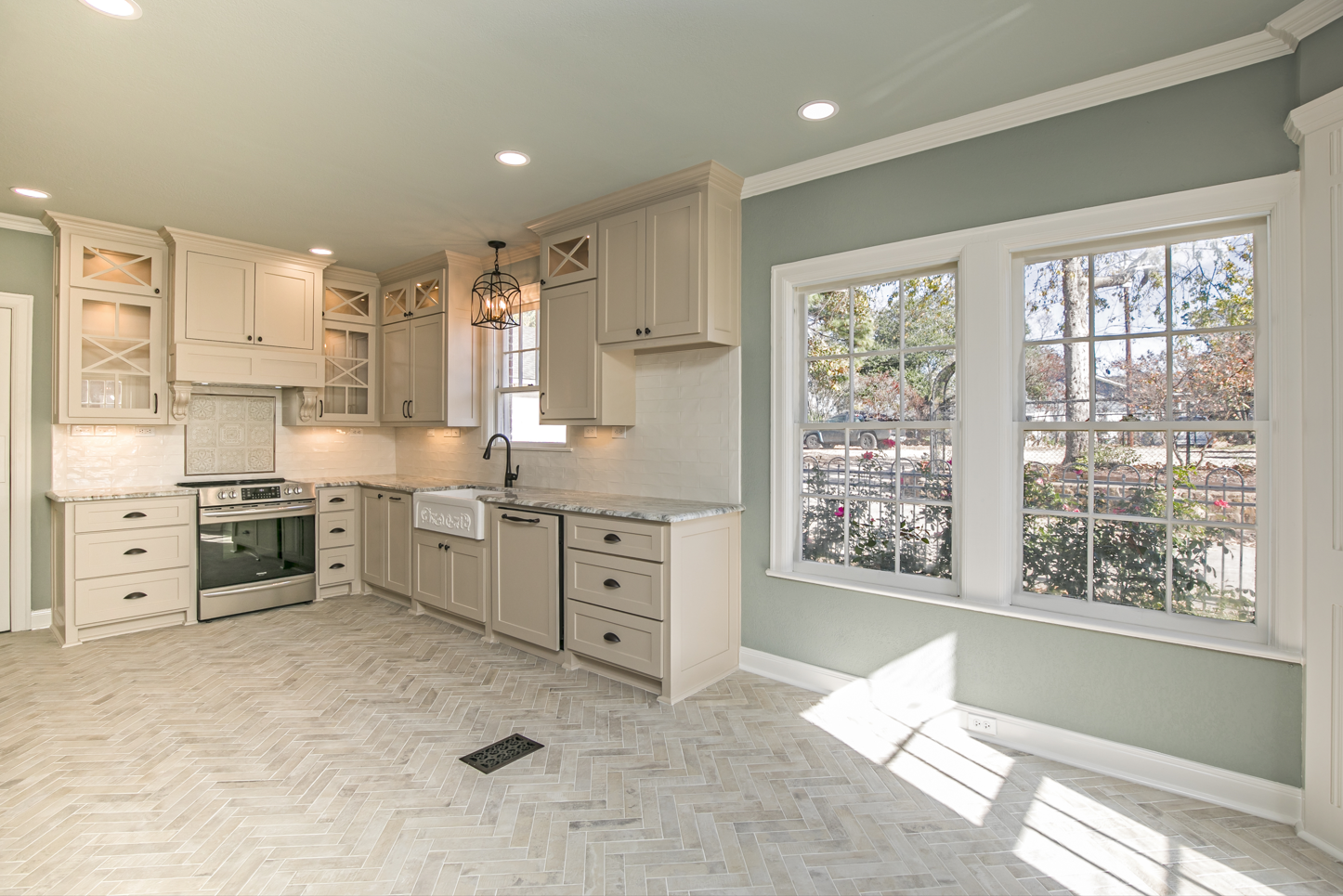A kitchen with white cabinets and stainless steel appliances and a lot of windows.
