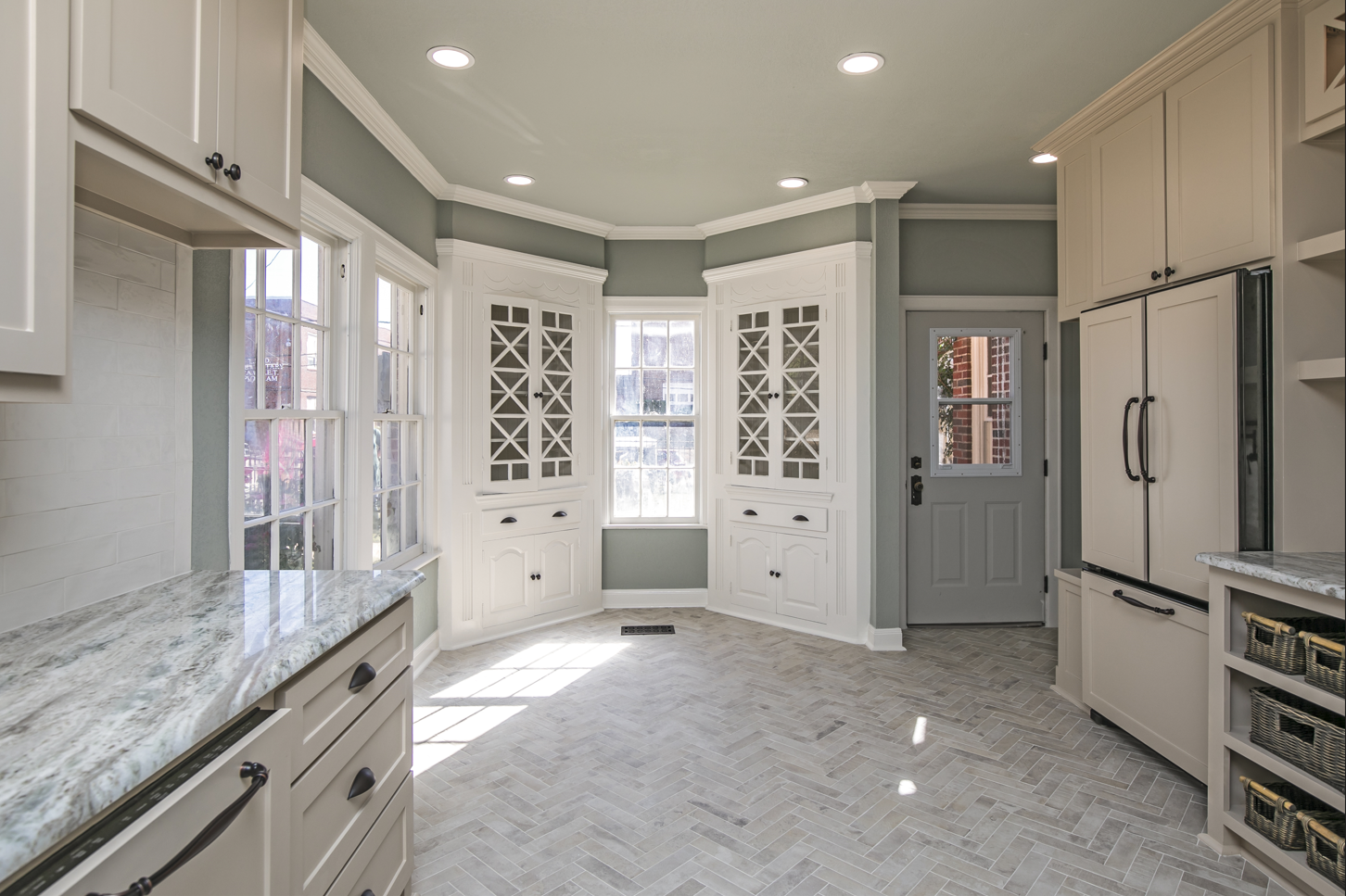A kitchen with white cabinets , granite counter tops , and a gray door.