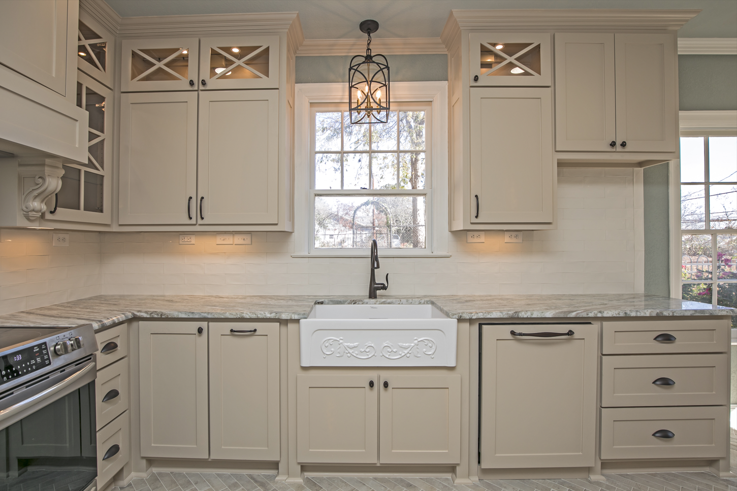 A kitchen with white cabinets , granite counter tops , a sink and a window.