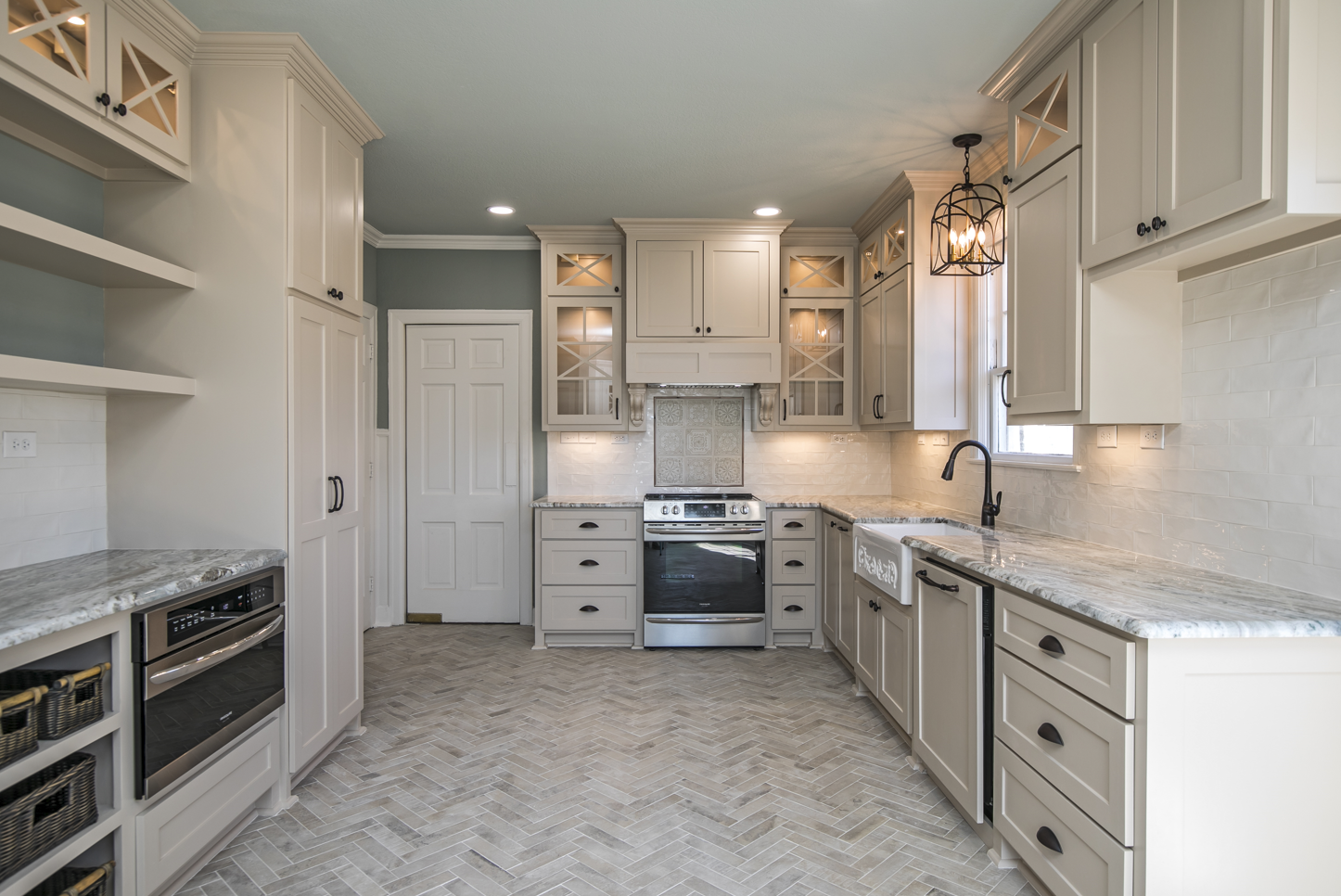 A kitchen with white cabinets , granite counter tops , stainless steel appliances and a stove.