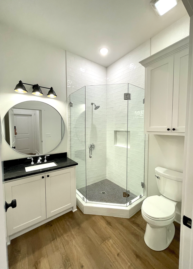 A bathroom with a toilet , sink , shower and mirror.