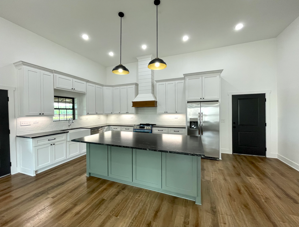 A kitchen with white cabinets , stainless steel appliances , and a large island.