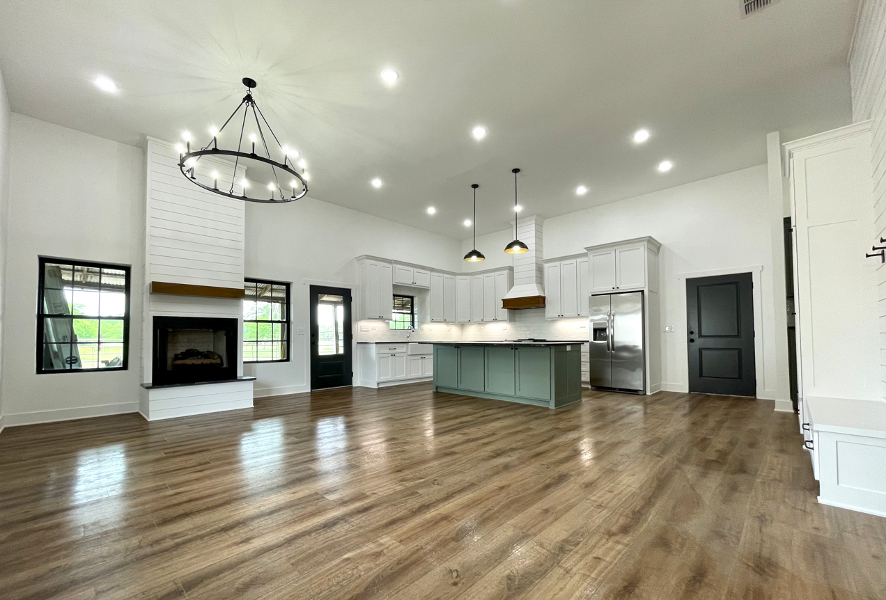 A large empty living room with hardwood floors and a fireplace.