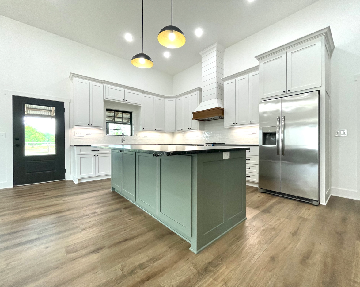 A kitchen with white cabinets , stainless steel appliances , and a large island.