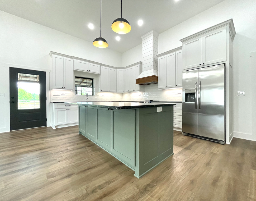 A kitchen with white cabinets , stainless steel appliances , and a large island.