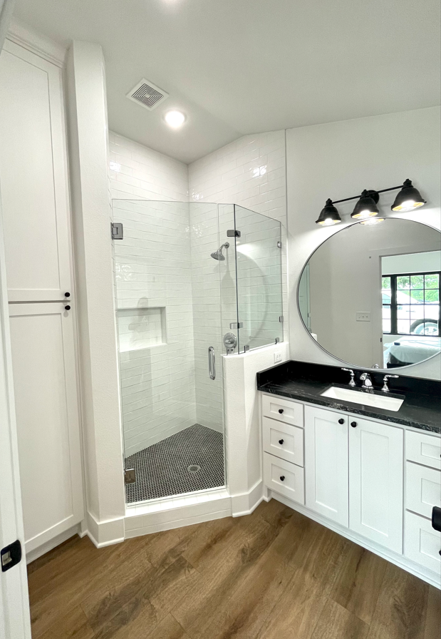 A bathroom with a walk in shower , sink and mirror.