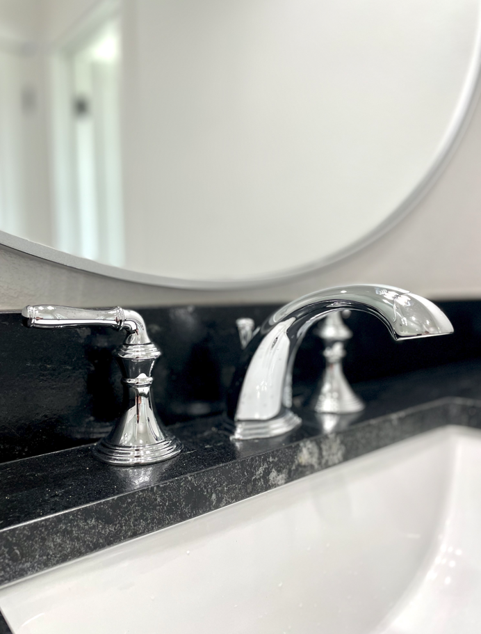 A bathroom sink with chrome faucets and a mirror.