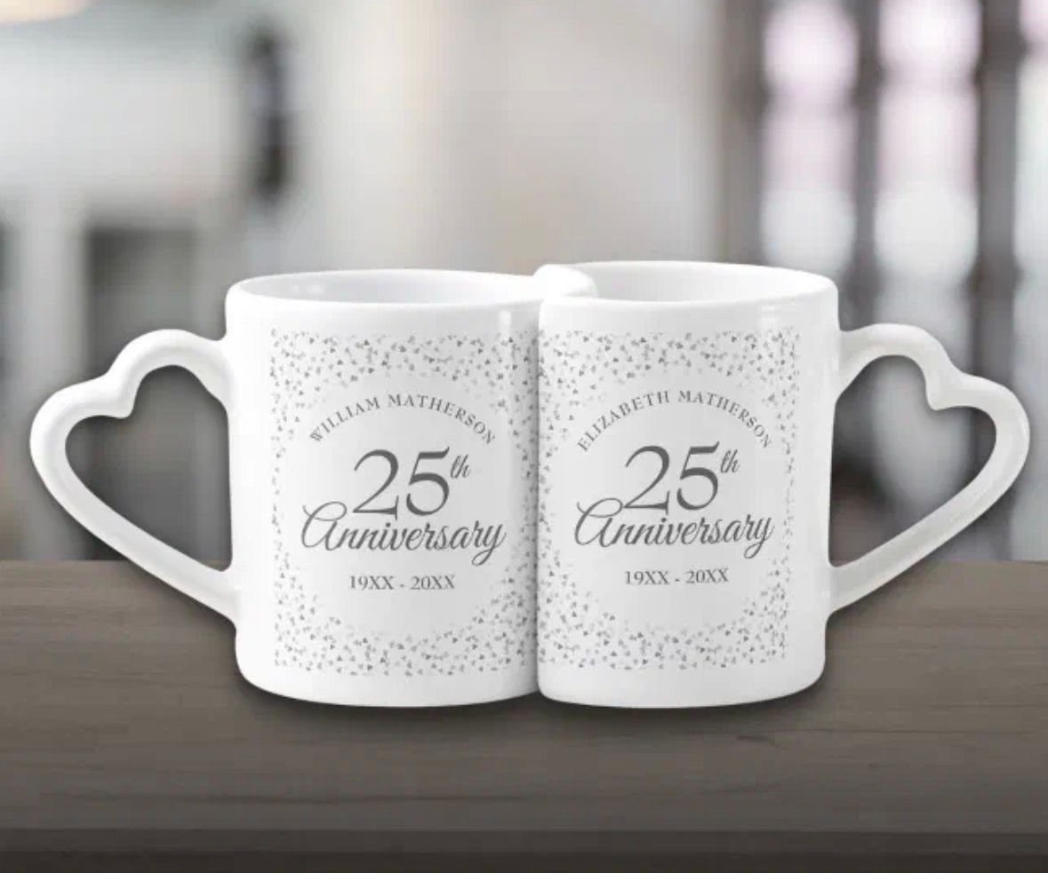 Two white mugs with heart-shaped handles; 25th Anniversary celebration design.