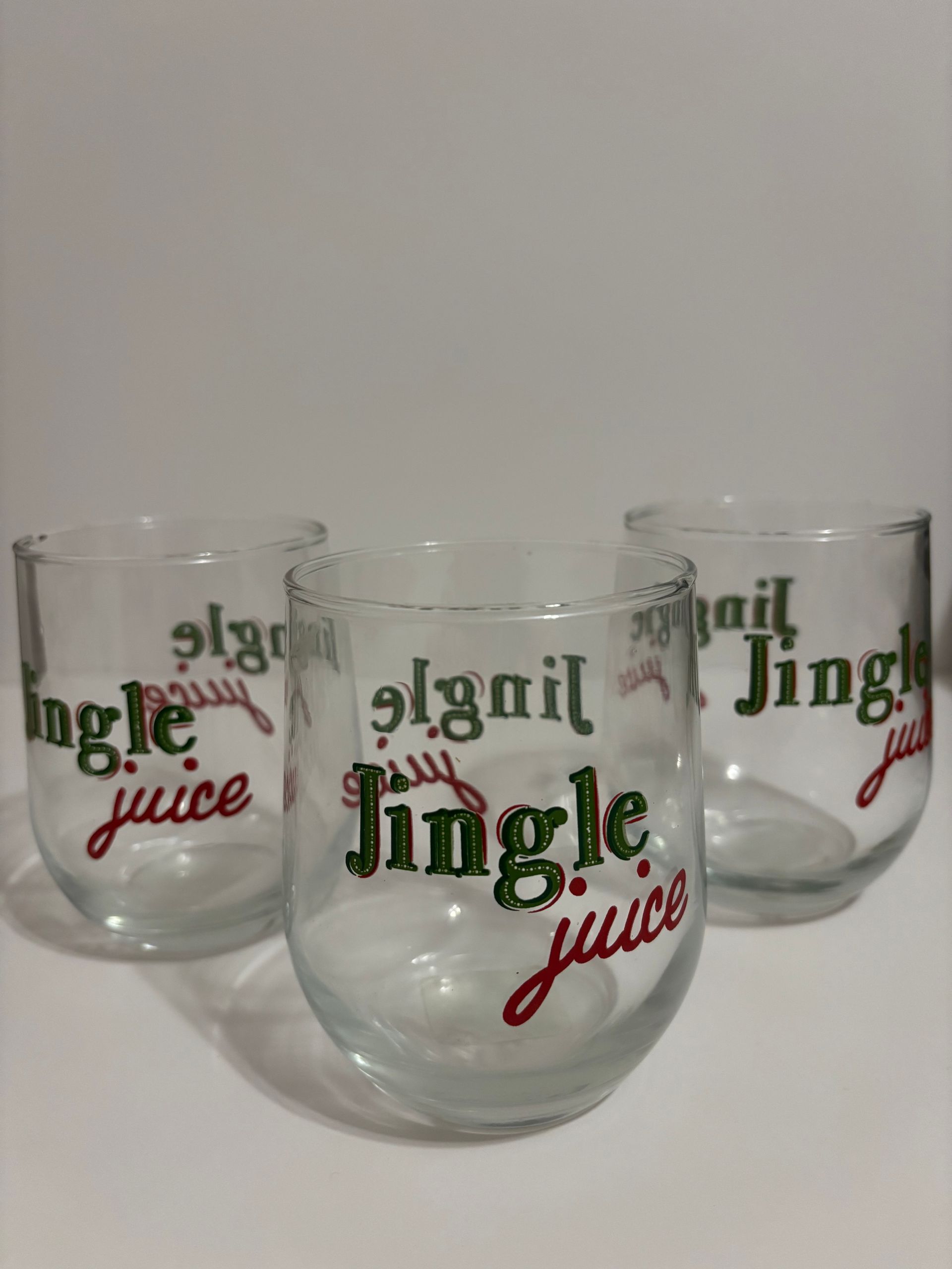 Four clear stemless glasses, each with 