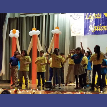 A group of children are on a stage in front of a sign that says lights nation