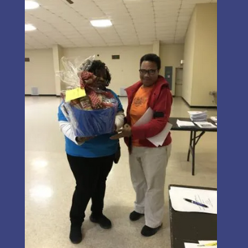 A woman in a blue shirt is holding a basket of food
