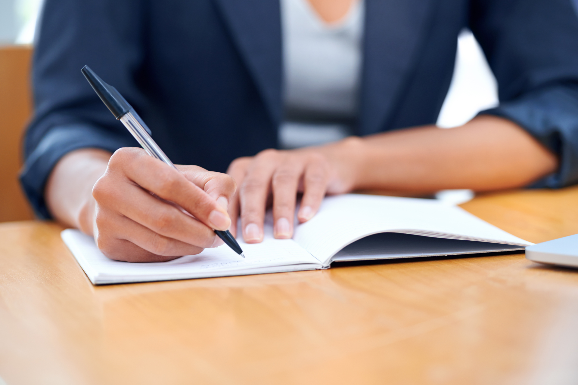 A woman is writing in a notebook with a pen