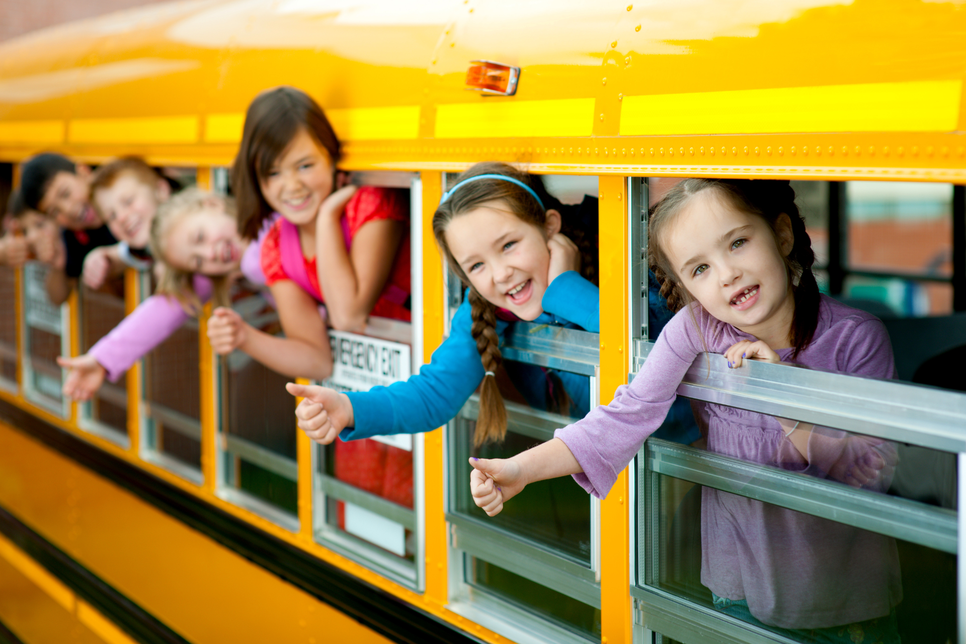 A group of children are looking out of the windows of a school bus.