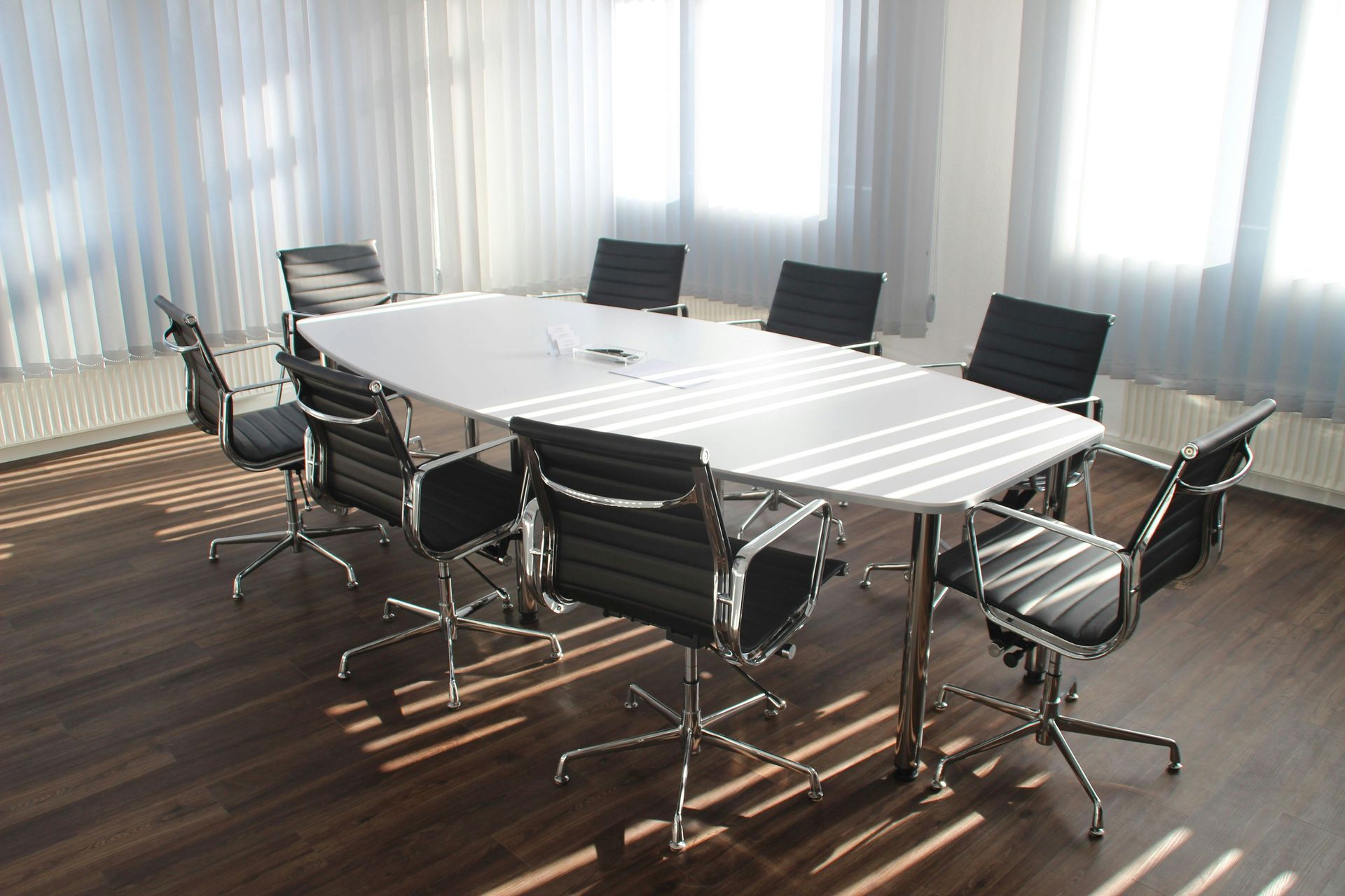 A conference room with a long table and black chairs