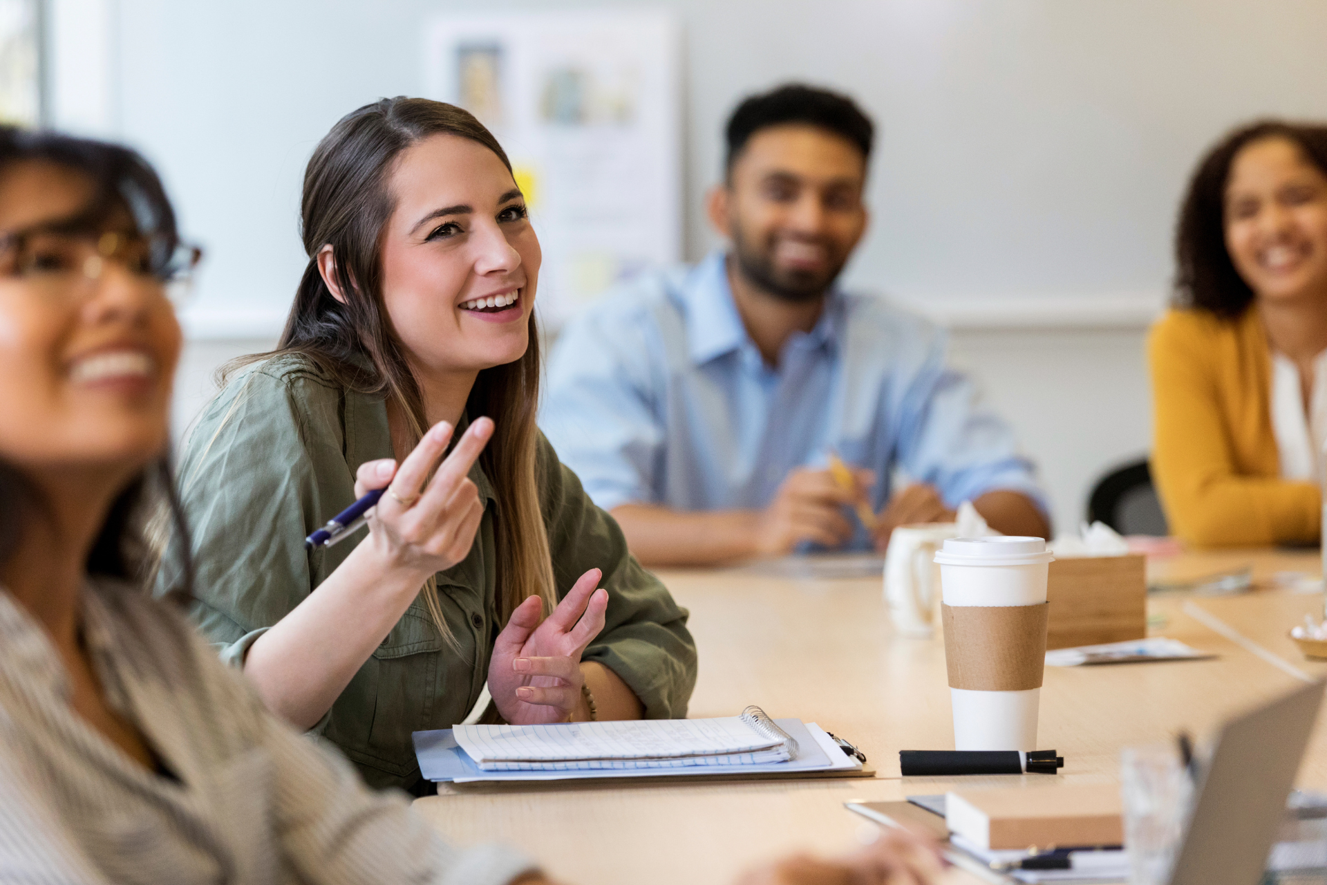 A group of people are sitting around a table having a meeting.