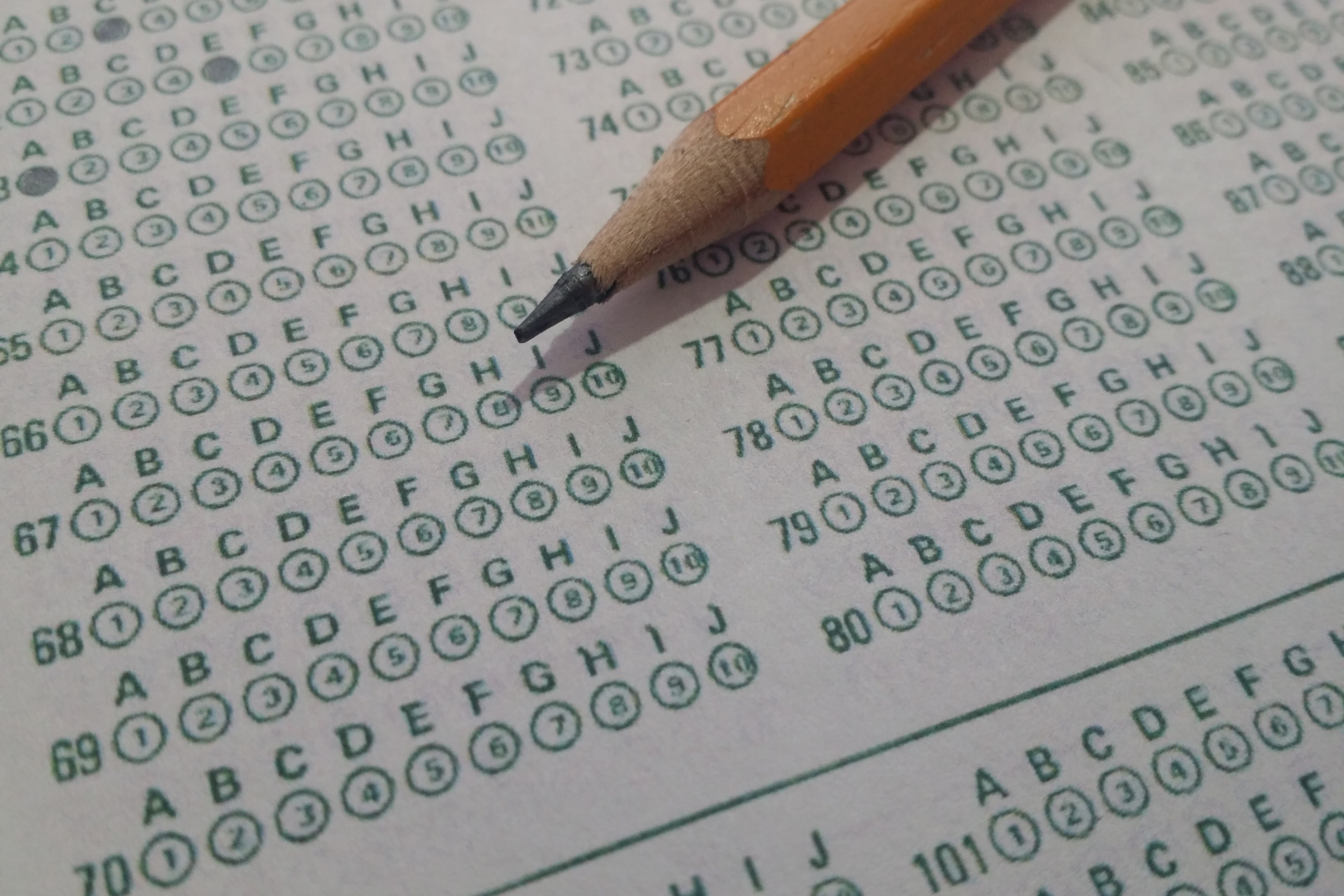 A pencil is sitting on top of a test with the letters abcdefghij written on it