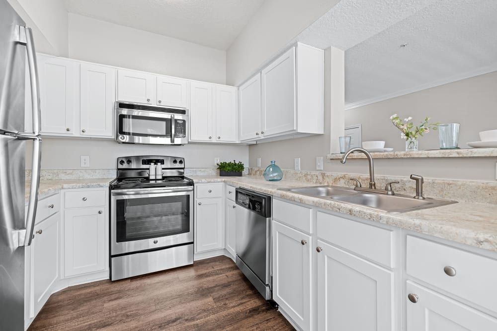 A kitchen with white cabinets, stainless steel appliances, a sink, and a refrigerator at Marquis at Silverton in Cary, NC.