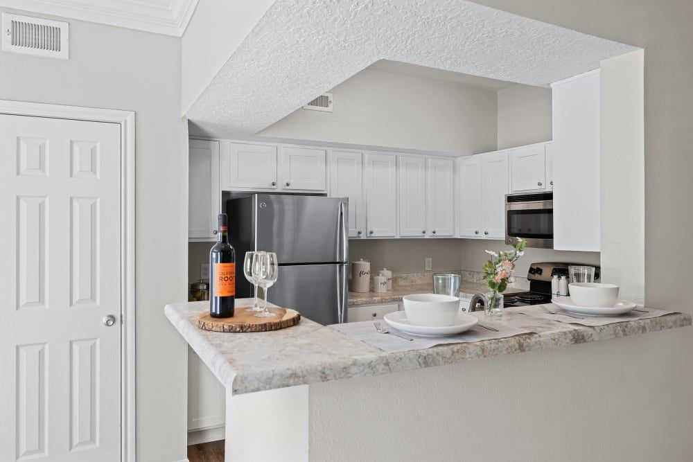 Apartment kitchen with white cabinets and a stainless steel refrigerator at Marquis at Silverton in Cary, NC.