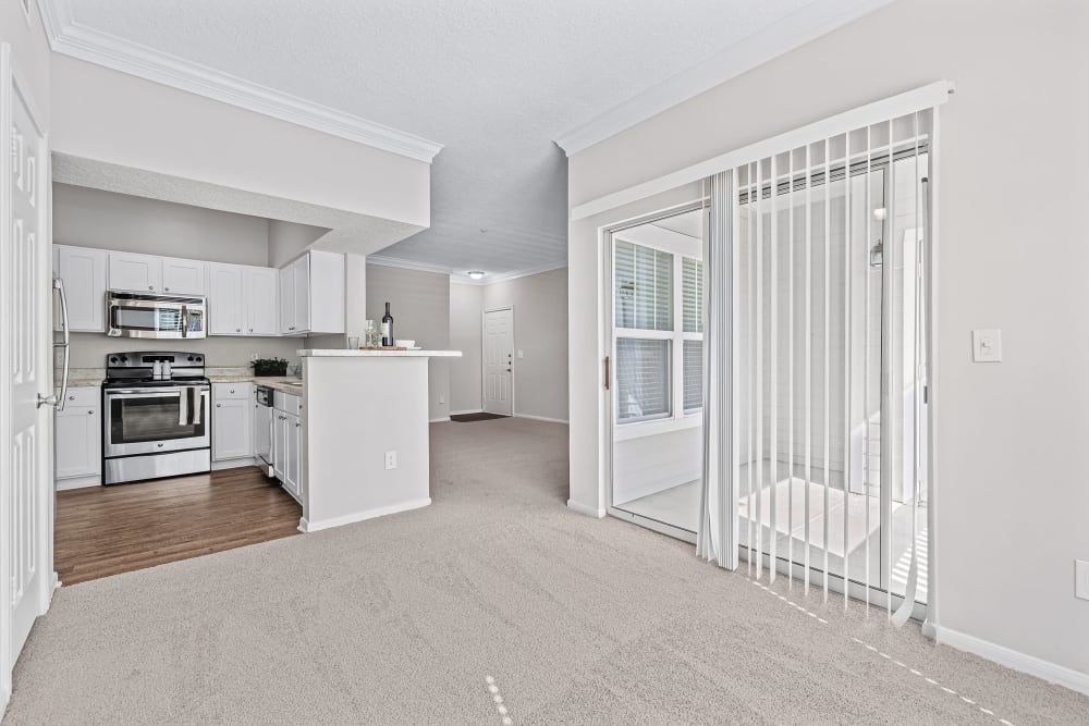 Empty apartment with open floor plan -  living room with a sliding glass door leading to a kitchen at Marquis at Silverton in Cary, NC.