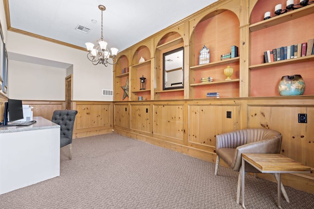 Business center with a desk, chairs, shelves, and a chandelier at Marquis at Silverton in Cary, NC.