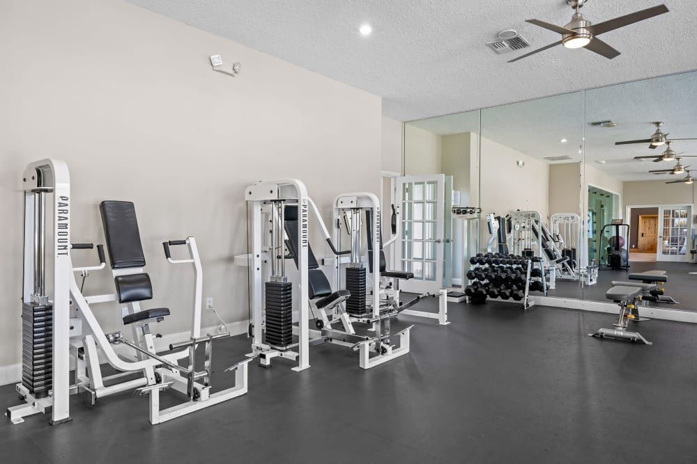 Apartment gym filled with lots of exercise equipment and a ceiling fan at Marquis at Silverton in Cary, NC.