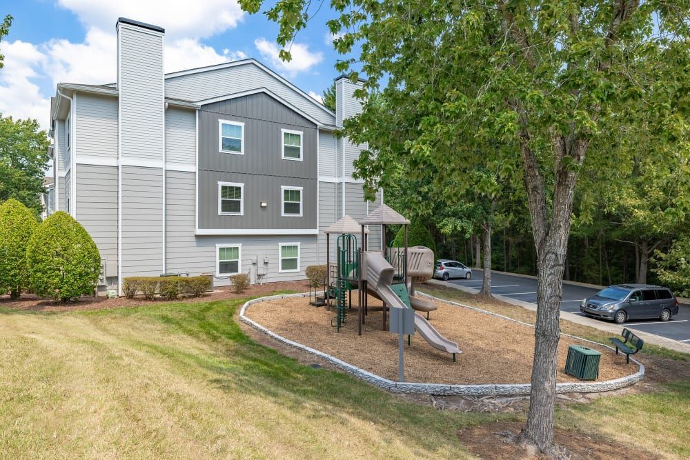 A playground is in front of a large apartment building at Marquis at Silverton in Cary, NC.