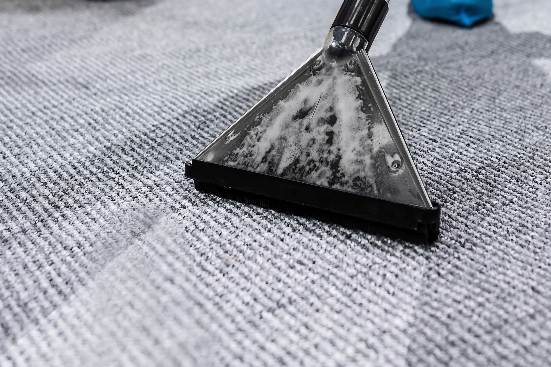 A person is cleaning a carpet with a vacuum cleaner.