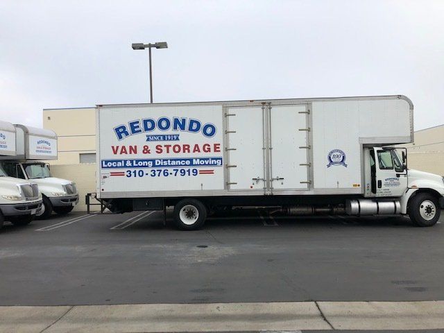 A moving company truck is parked in a lot with a large storage container. A moving company truck is parked in a lot with a large storage container.