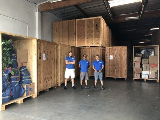 Three workers standing in a warehouse with large wooden storage crates. Three workers standing in a warehouse with large wooden storage crates.