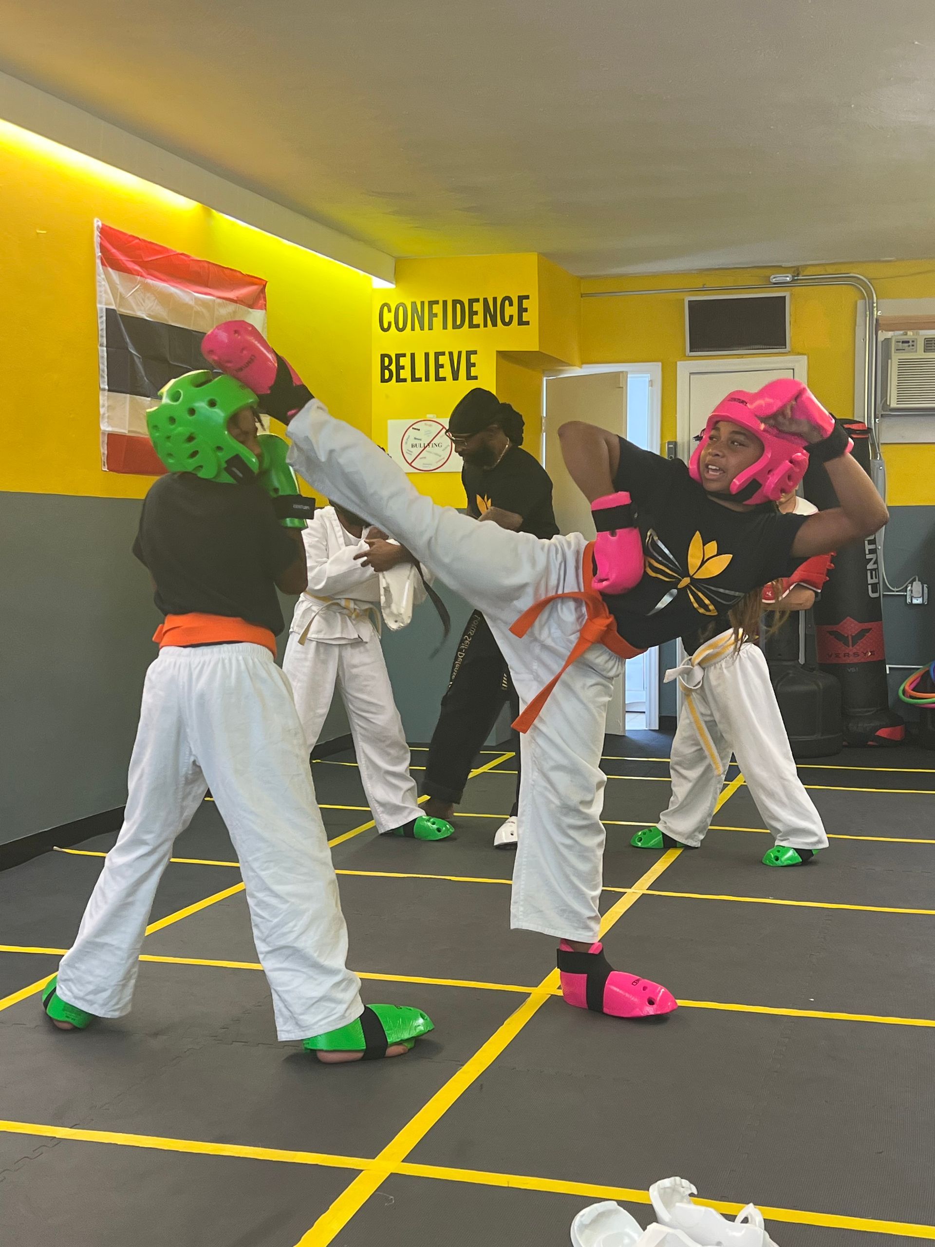 A group of kids are practicing martial arts in front of a sign that says confidence believe