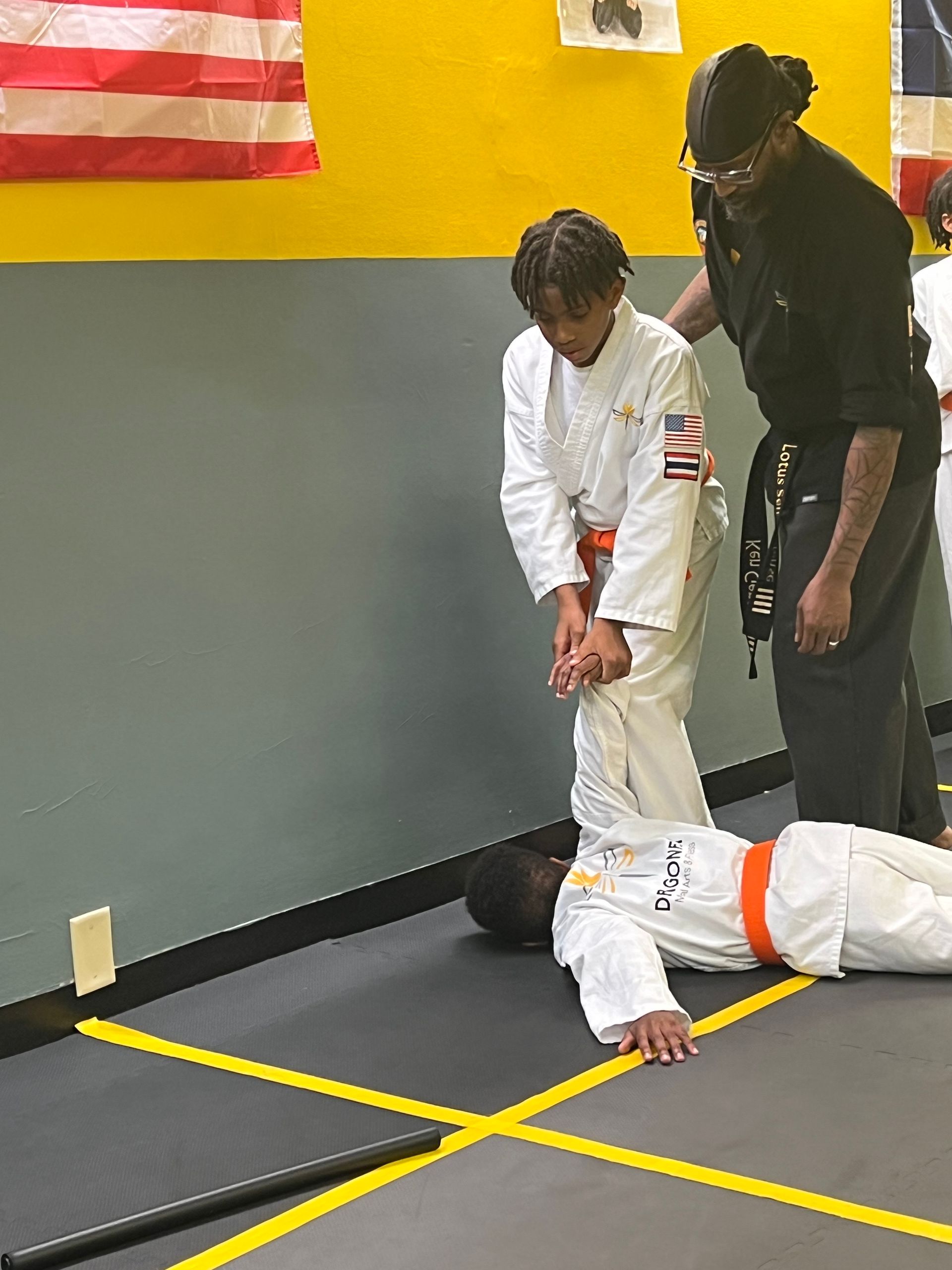 A young boy is laying on the floor in a karate class