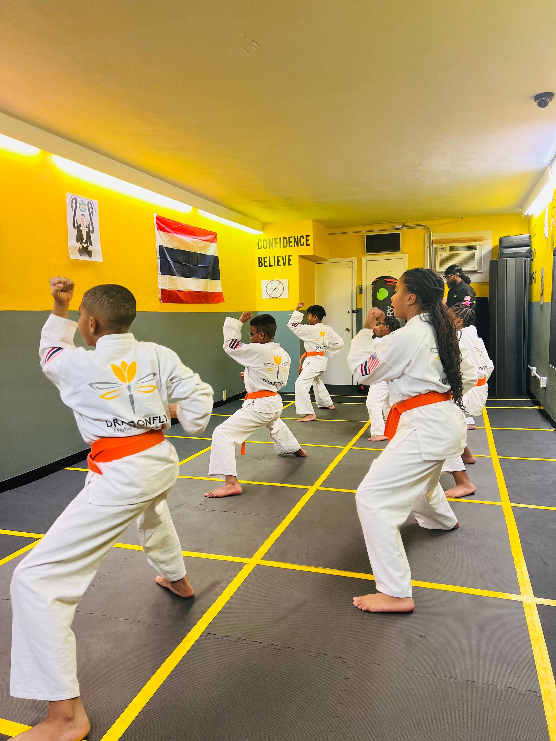 A group of children are practicing martial arts in a gym.