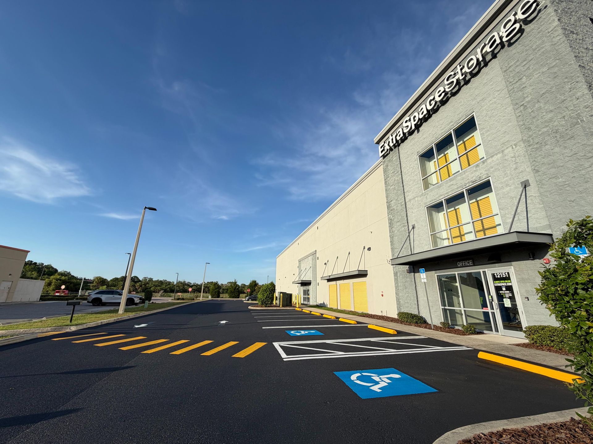Exterior of a modern gray building with accessible parking spaces and yellow-striped pavement under a blue sky