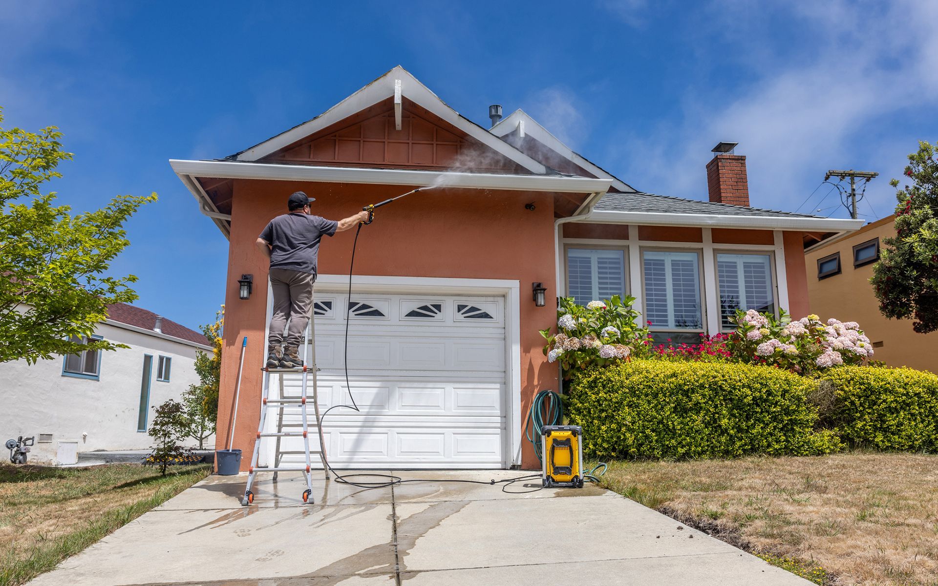 A man is cleaning the roof of a house with a high pressure washer.