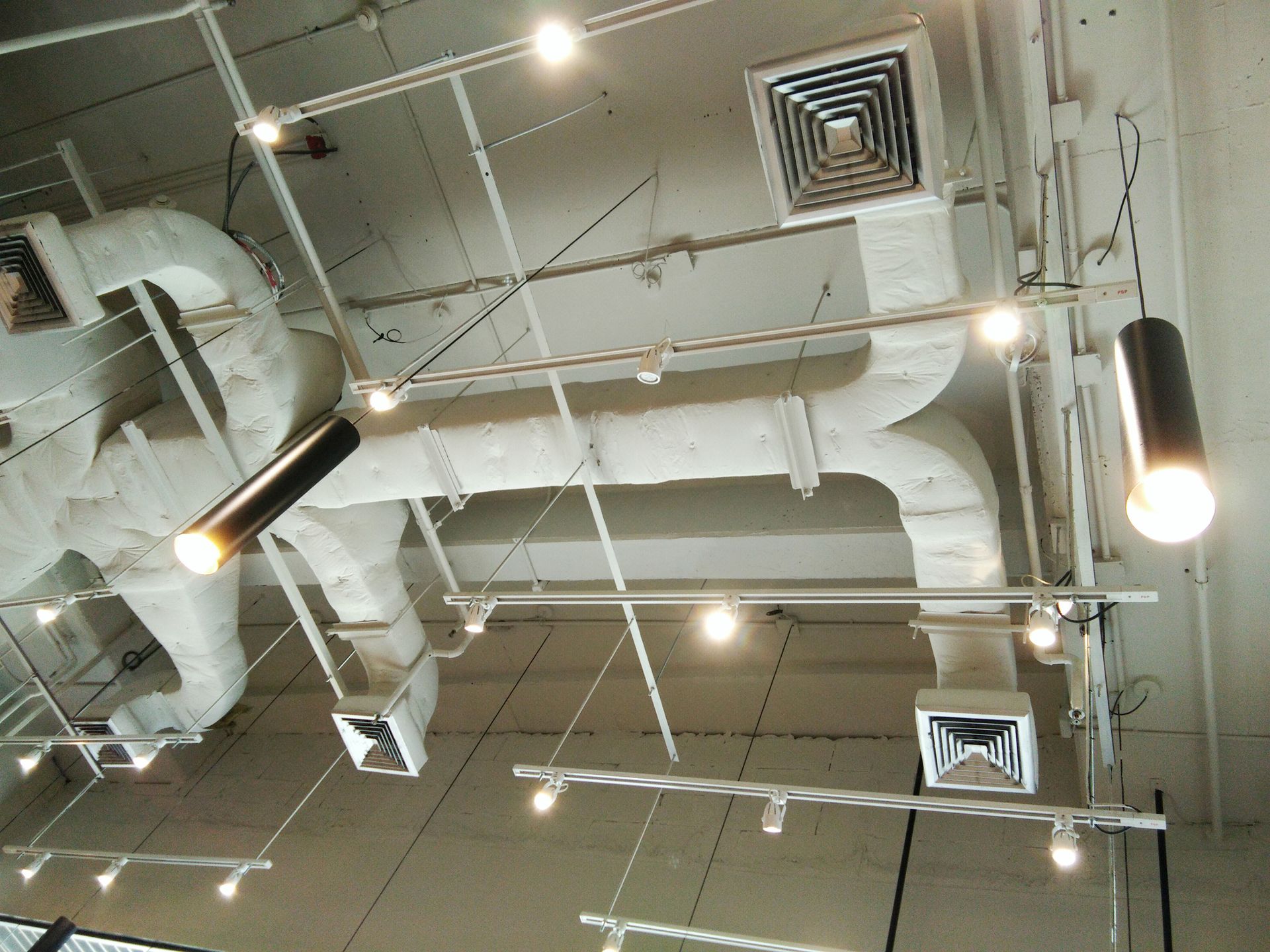A woman is cleaning the ceiling with a mop in a living room.