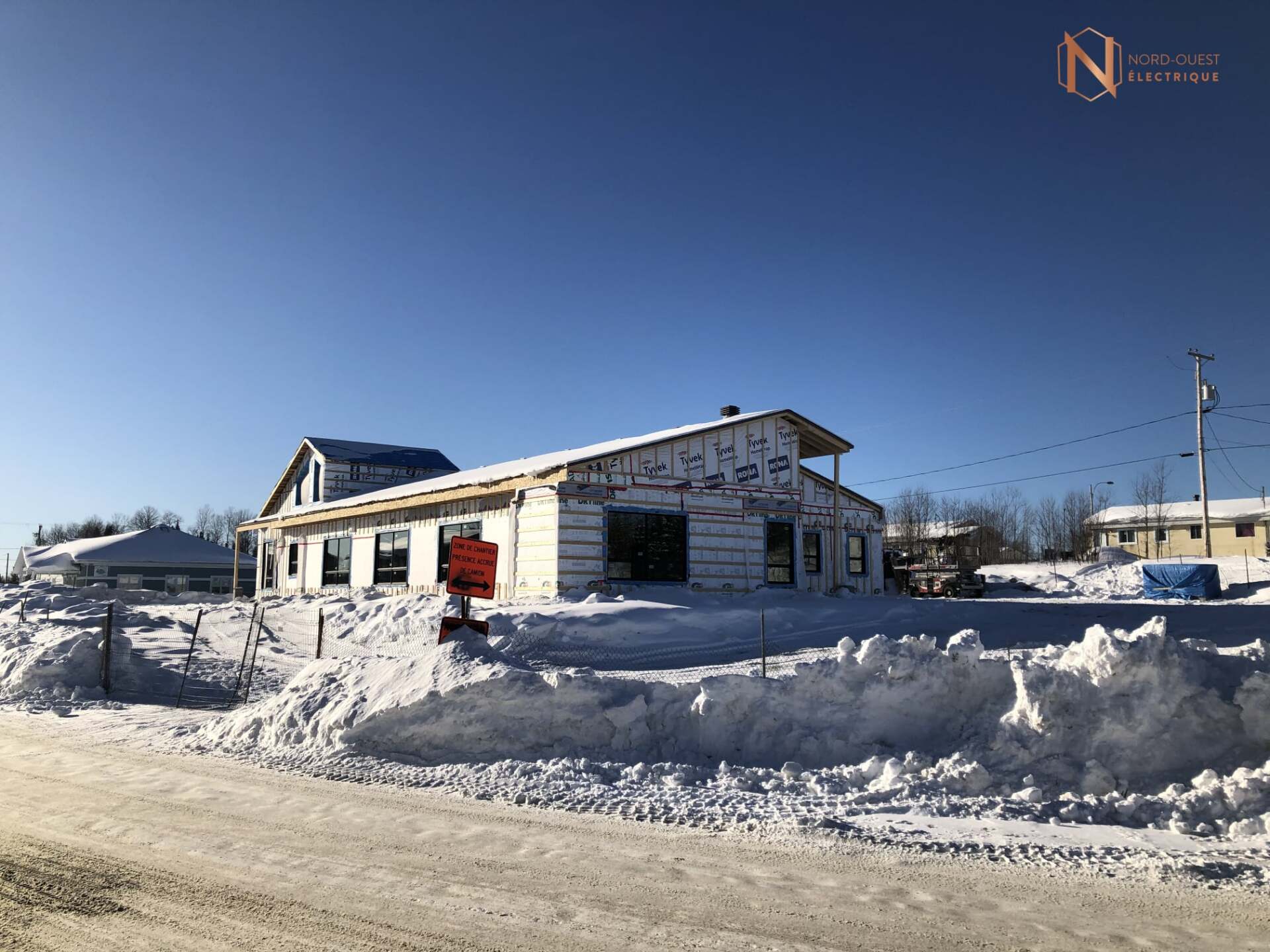 Une maison est en construction dans la neige à côté d'une route.