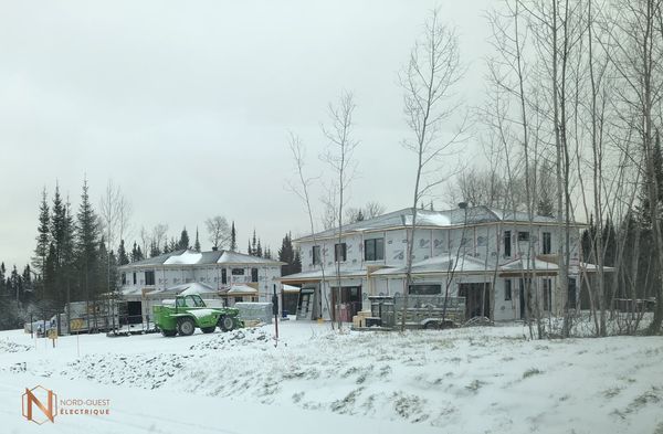 Un camion vert est garé devant une maison en construction sous la neige.