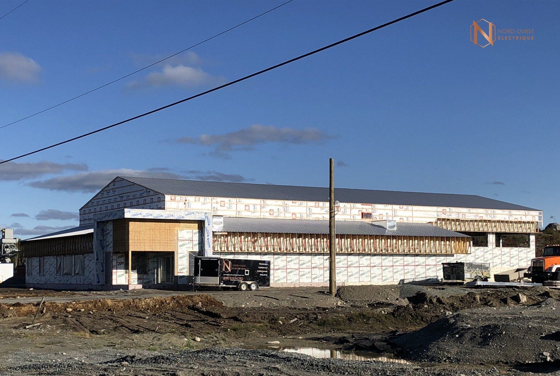 Un grand bâtiment est en construction au milieu d'un champ de terre.