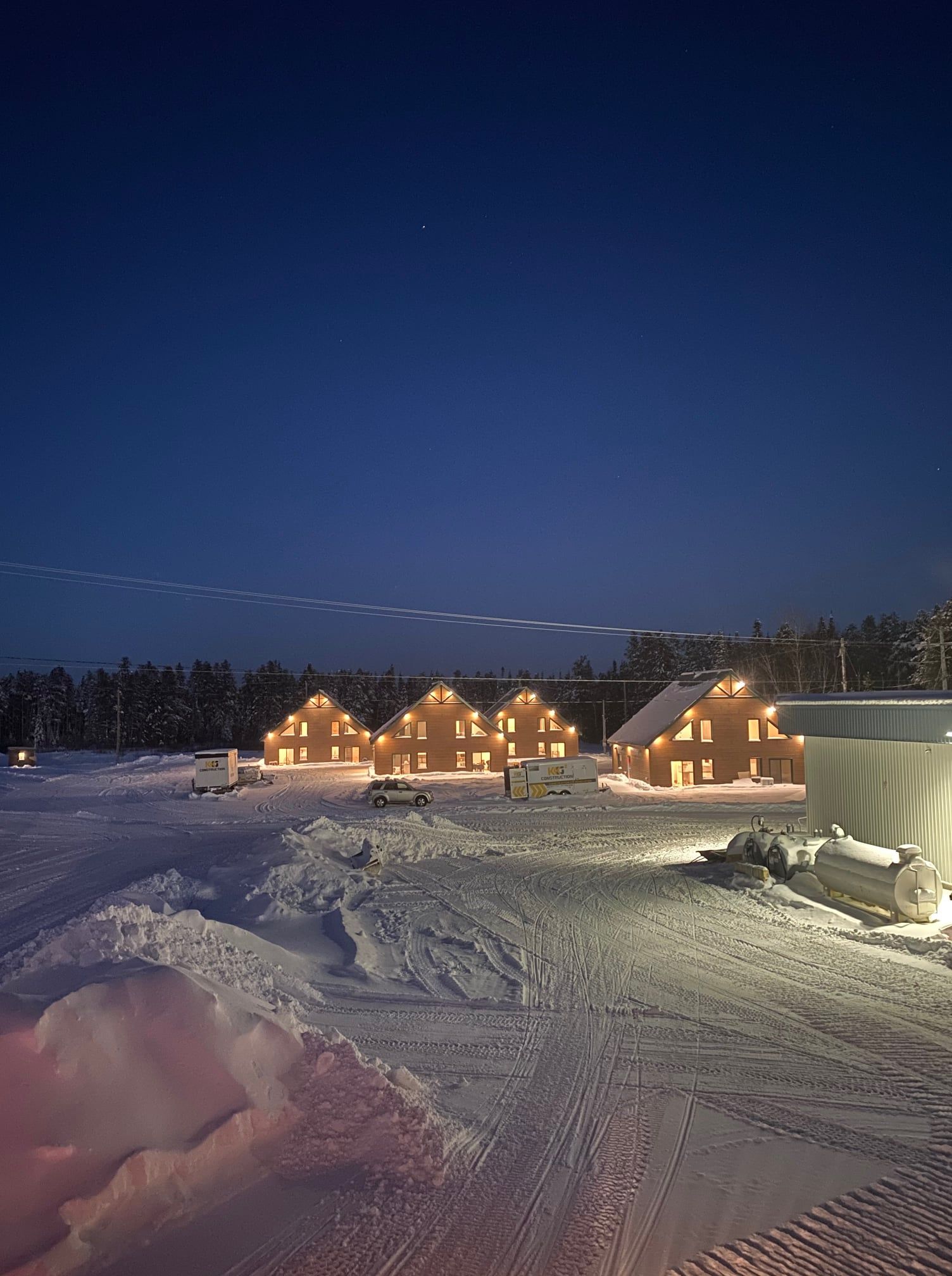 Un groupe de maisons est illuminé par la neige la nuit.